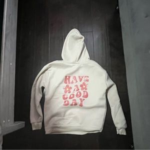 A cream colored hoodie with writing on the back that says “Have A Good Day”